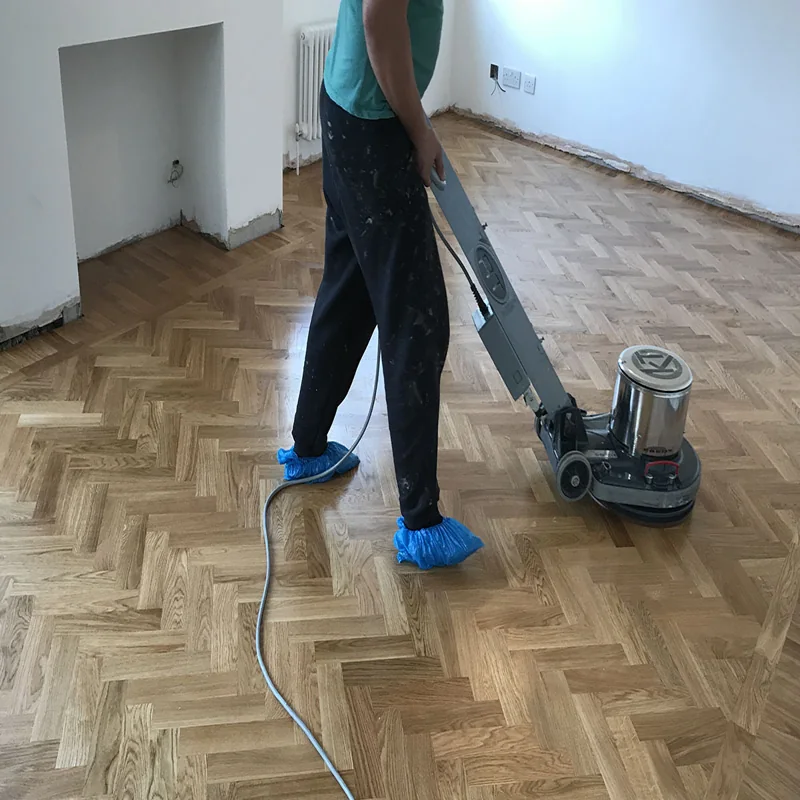 Polishing herringbone wood floor during renovation.